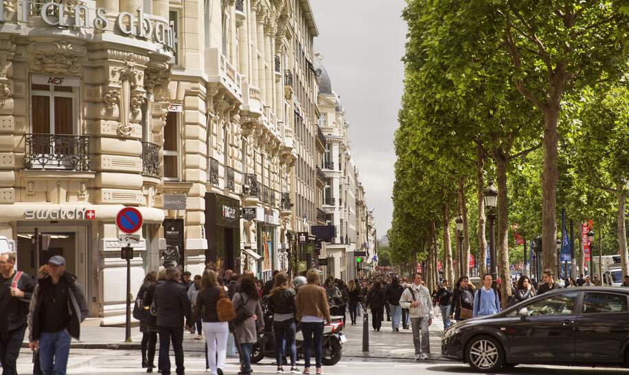 Passanten gehen auf der Avenue des Champs-Élysées in Paris shoppen . | © Gettyimages.com/MediaProduction